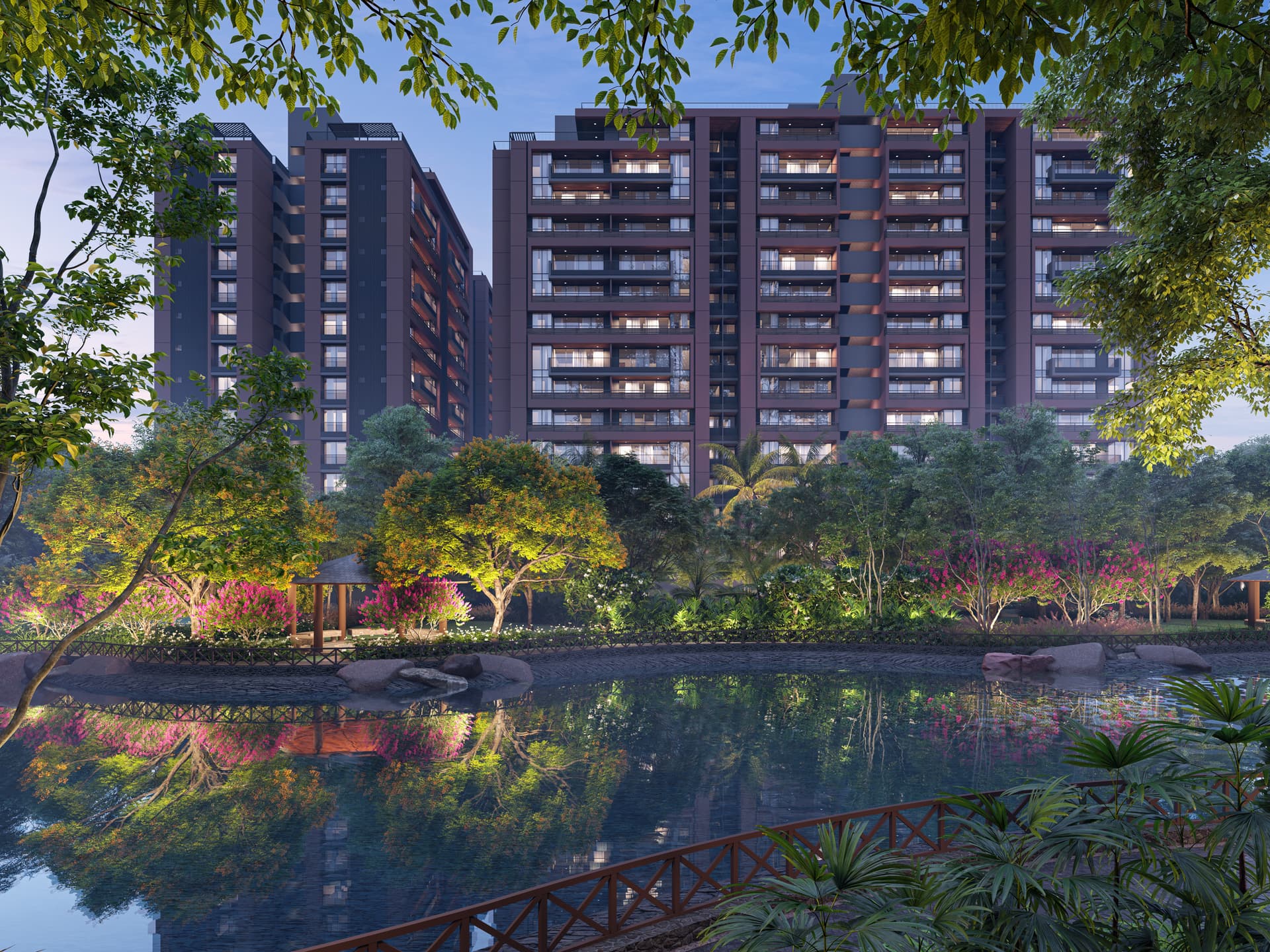 A Parmeshwar Group residential development at dusk, seen across a landscaped lake through the trees.